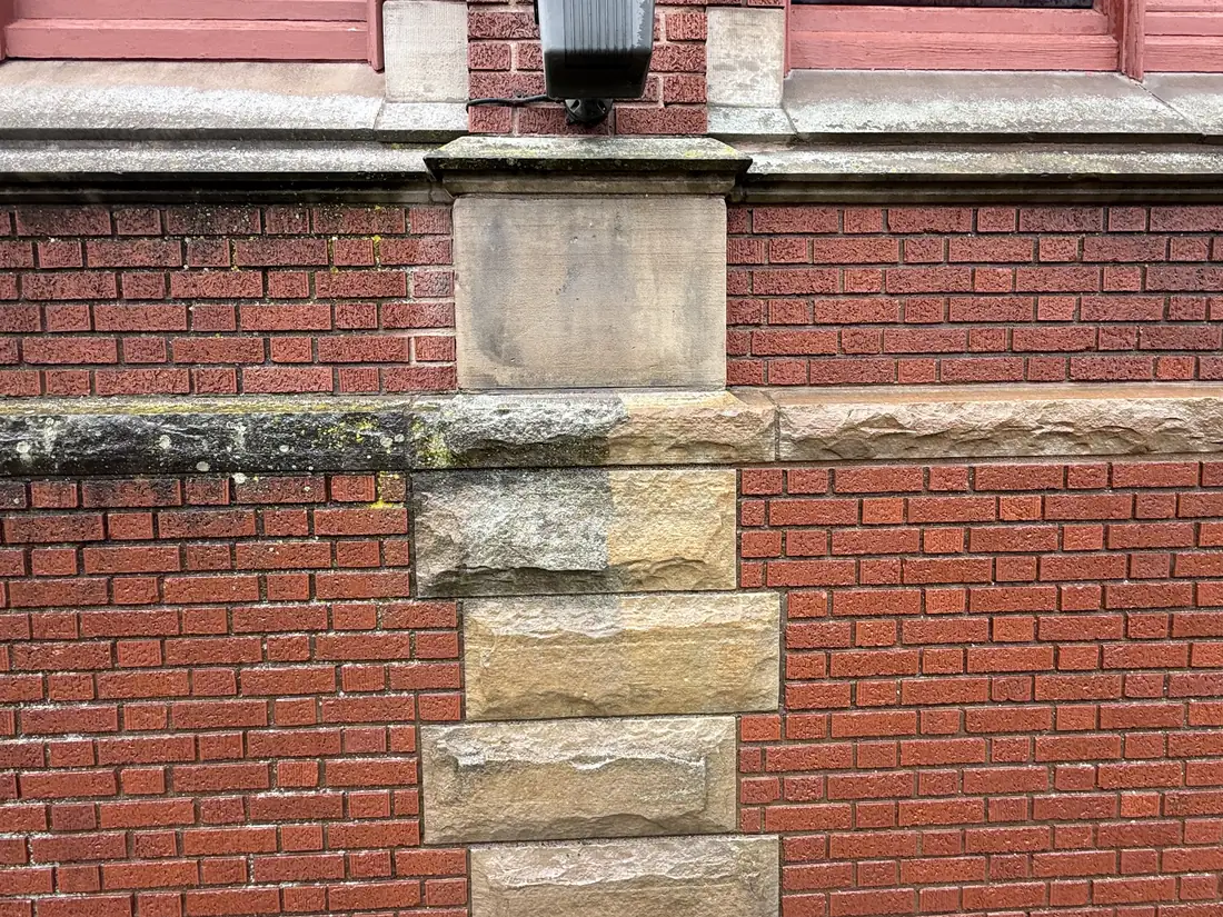 In-progress commercial masonry cleaning in Canton, Ohio. Dirty stone on the left, freshly cleaned stone on the right, in the same frame.